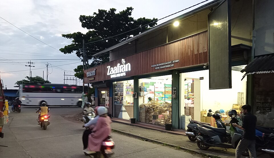 Bustling market scene in Kozhikode Big Bazaar displaying open sacks of wholesale spices, rice, and local commodities on a shop veranda