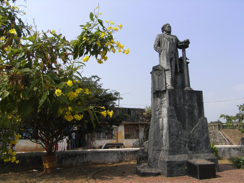 length stone statue of Dr. Hermann Gundert standing on a pedestal at Illikunnu, Thalassery