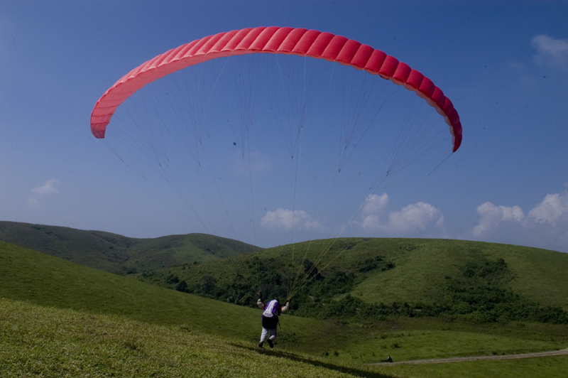 Paragliding above the rolling green meadows and pine-fringed tea gardens of Vagamon hill station in Idukki Kerala